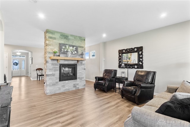 4978 Renaissance Park Dr, Middletown, OH 45005 - living room with arched walkways, light wood-style floors, a stone fireplace, recessed lighting, and baseboards