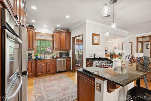 1134 N Webb Rd, Adams Twp, OH 45177 - kitchen with appliances with stainless steel finishes, a kitchen bar, ornamental molding, brown cabinetry, and light wood finished floors