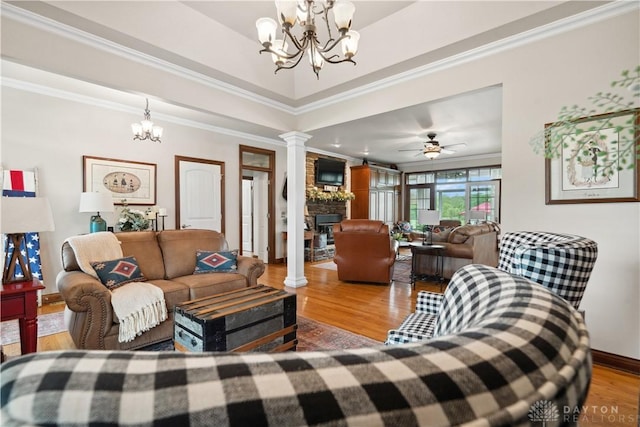 1134 N Webb Rd, Adams Twp, OH 45177 - living area with decorative columns, a chandelier, wood finished floors, crown molding, and a stone fireplace