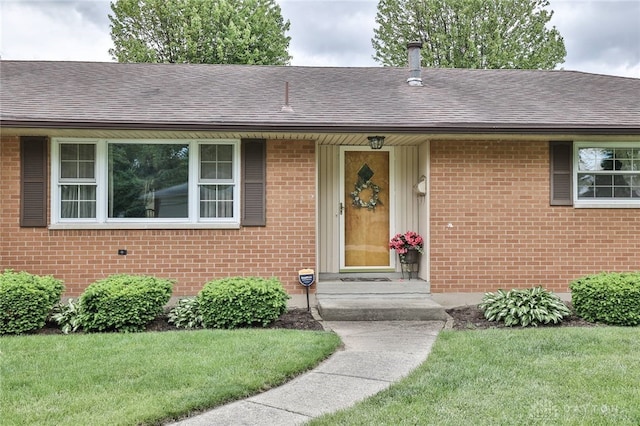 300 Magnolia Ave, Englewood, OH 45322 - doorway to property with a shingled roof, brick siding, and a yard