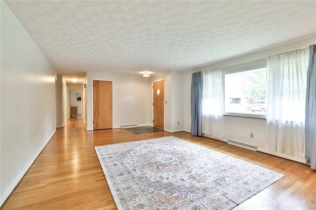 300 Magnolia Ave, Englewood, OH 45322 - unfurnished living room with a baseboard heating unit, light wood-style flooring, and baseboards
