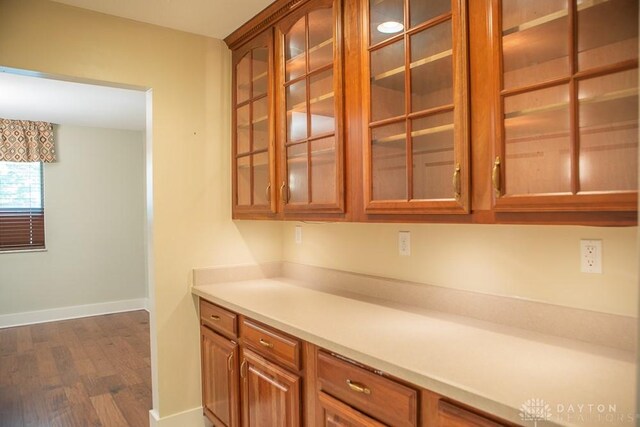 316 Honey Jane Dr, Beavercreek, OH 45434 - kitchen featuring dark wood-style flooring, baseboards, glass insert cabinets, brown cabinetry, and light countertops
