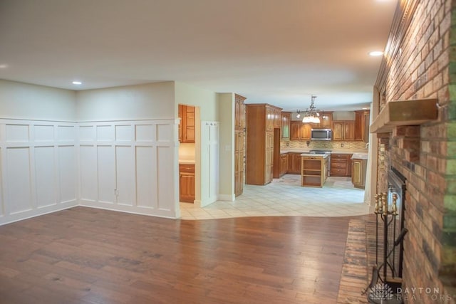 316 Honey Jane Dr, Beavercreek, OH 45434 - unfurnished living room with a decorative wall, light wood-style flooring, a chandelier, recessed lighting, and a fireplace