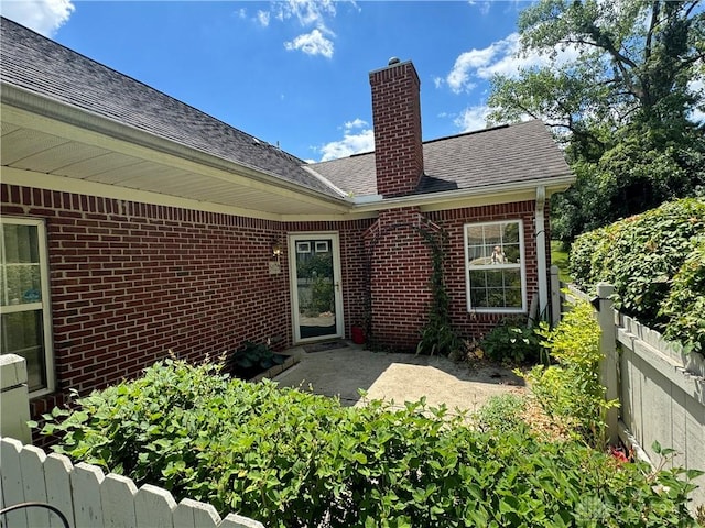 5023 Crescent Ridge Dr, Clayton, OH 45315 - back of property featuring brick siding, a chimney, a shingled roof, and a patio