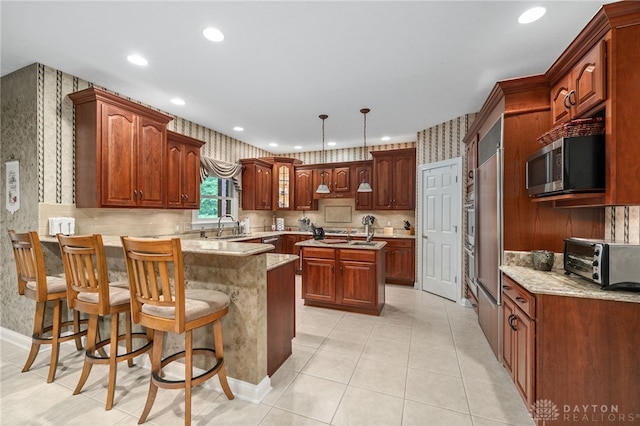 7607 Stone Ridge Dr, Springboro, OH 45066 - kitchen featuring stainless steel microwave, a peninsula, wallpapered walls, a sink, and recessed lighting
