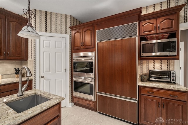 7607 Stone Ridge Dr, Springboro, OH 45066 - kitchen with built in appliances, a sink, light tile patterned floors, tasteful backsplash, and light stone counters