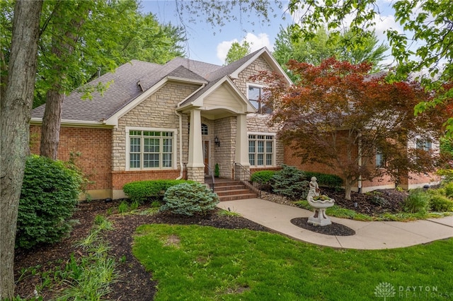 7607 Stone Ridge Dr, Springboro, OH 45066 - craftsman-style house featuring stone siding, roof with shingles, a front yard, and brick siding
