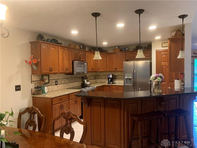 2460 Coriander Ct, Troy, OH 45373 - kitchen with stainless steel appliances, a breakfast bar area, a peninsula, pendant lighting, and brown cabinets