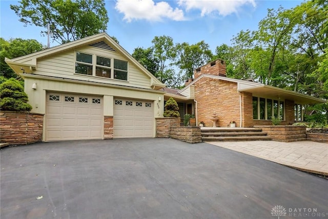 450 Ridgewood Ave, Oakwood, OH 45409 - view of front of home with stone siding, driveway, and a chimney