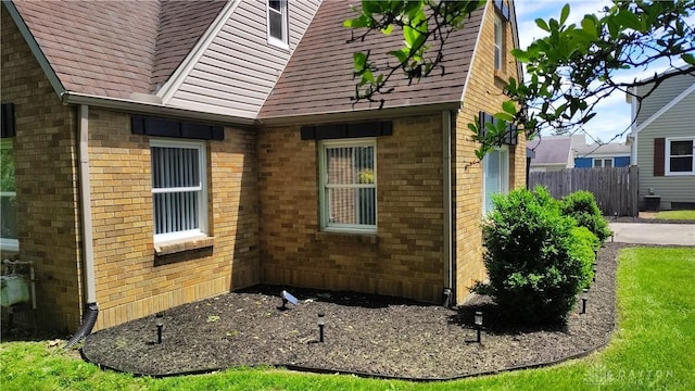 413 W Lake Ave, New Carlisle, OH 45344 - view of side of property with brick siding, roof with shingles, and central air condition unit