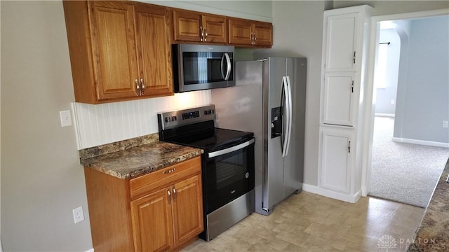 413 W Lake Ave, New Carlisle, OH 45344 - kitchen featuring stainless steel appliances, brown cabinets, dark countertops, and baseboards