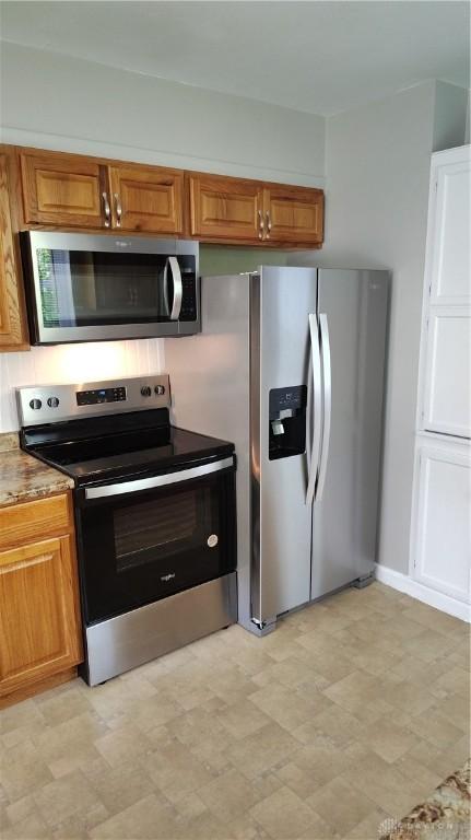 413 W Lake Ave, New Carlisle, OH 45344 - kitchen featuring stainless steel appliances, brown cabinetry, and light flooring