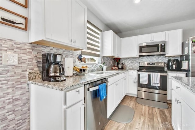 1852 Amelia Way, Dayton, OH 45439 - kitchen with appliances with stainless steel finishes, white cabinetry, light stone counters, light wood finished floors, and backsplash