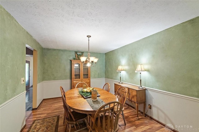 5135 Lamonte Dr, Fairfield, OH 45014 - dining room with wood finished floors, a textured ceiling, a chandelier, and a wainscoted wall