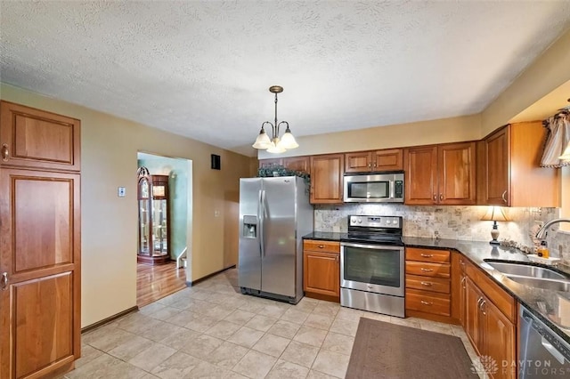 5135 Lamonte Dr, Fairfield, OH 45014 - kitchen featuring appliances with stainless steel finishes, a sink, brown cabinetry, backsplash, and a textured ceiling