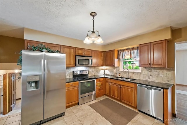 5135 Lamonte Dr, Fairfield, OH 45014 - kitchen featuring stainless steel appliances, a sink, brown cabinets, decorative backsplash, and a textured ceiling