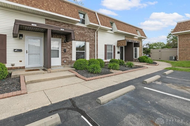 1050 Frederick Dr, Xenia, OH 45385 - view of front facade with central air condition unit, uncovered parking, a gate, mansard roof, and brick siding
