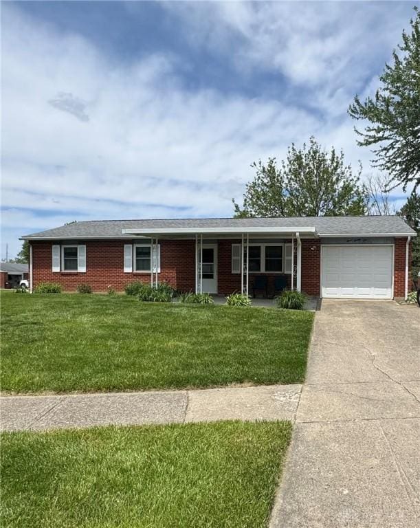 326 Little League Dr, Eaton, OH 45320 - ranch-style home featuring brick siding, an attached garage, driveway, covered porch, and a front lawn