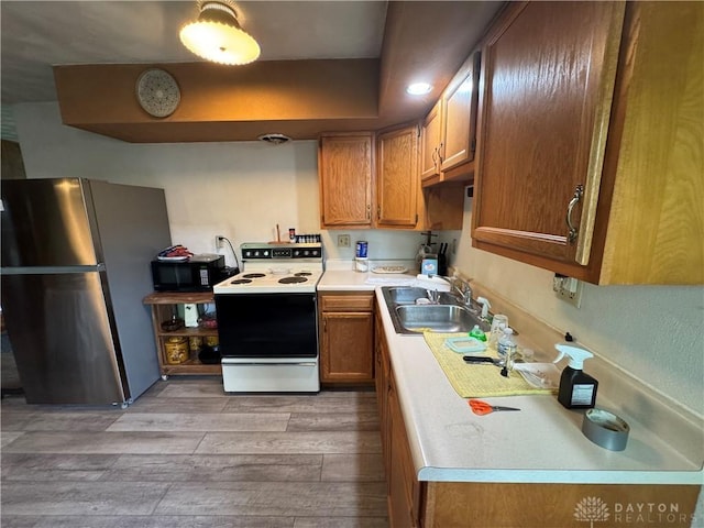 326 Little League Dr, Eaton, OH 45320 - kitchen with freestanding refrigerator, range with electric cooktop, a sink, light wood-style floors, and brown cabinets