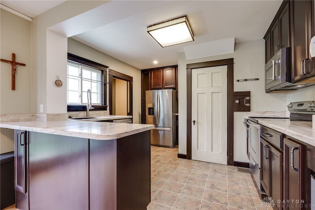 1809 Shroyer Rd, Oakwood, OH 45419 - kitchen with appliances with stainless steel finishes, a peninsula, dark brown cabinetry, and light stone countertops