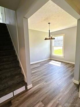 304 W Walnut St, Botkins, OH 45306 - unfurnished dining area with baseboards, stairway, wood finished floors, and a chandelier