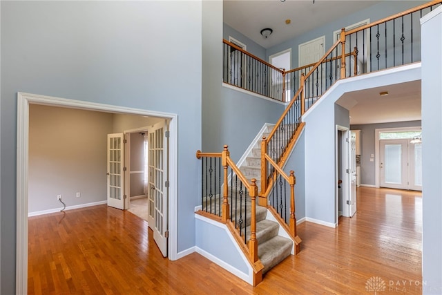 6265 Amberley Ct, Liberty Twp, OH 45044 - stairway featuring french doors, wood finished floors, a towering ceiling, and baseboards