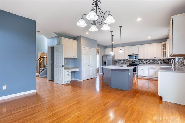 6265 Amberley Ct, Liberty Twp, OH 45044 - kitchen with appliances with stainless steel finishes, a sink, backsplash, white cabinets, and a kitchen island