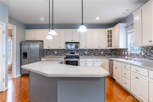 6265 Amberley Ct, Liberty Twp, OH 45044 - kitchen with appliances with stainless steel finishes, a sink, light wood-style flooring, decorative backsplash, and a kitchen island