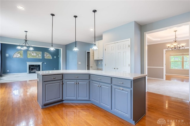 6265 Amberley Ct, Liberty Twp, OH 45044 - kitchen with a chandelier, open floor plan, light wood-type flooring, light countertops, and a glass covered fireplace