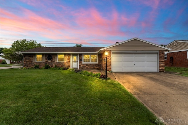 668 Dakota Dr, Xenia, OH 45385 - ranch-style home featuring concrete driveway, an attached garage, a yard, and brick siding