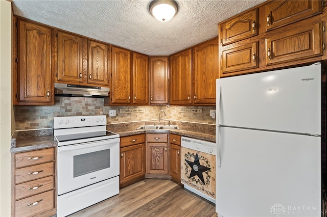 668 Dakota Dr, Xenia, OH 45385 - kitchen with white appliances, under cabinet range hood, a sink, brown cabinets, and a textured ceiling