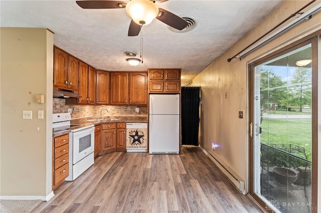 668 Dakota Dr, Xenia, OH 45385 - kitchen featuring white appliances, a baseboard radiator, under cabinet range hood, brown cabinetry, and a sink