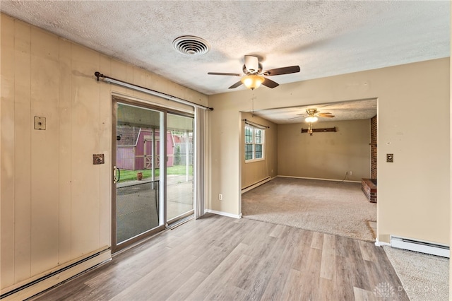 668 Dakota Dr, Xenia, OH 45385 - spare room with a baseboard heating unit, a ceiling fan, wood finished floors, and a textured ceiling