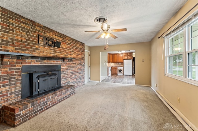 668 Dakota Dr, Xenia, OH 45385 - unfurnished living room with a baseboard radiator, light colored carpet, plenty of natural light, a wood stove, and a textured ceiling
