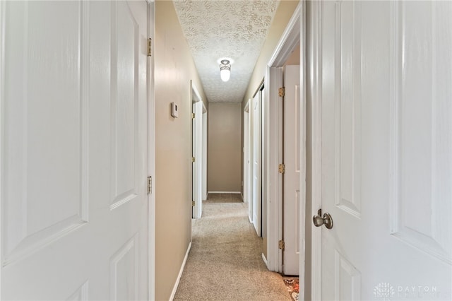 668 Dakota Dr, Xenia, OH 45385 - hall featuring a textured ceiling, light colored carpet, and baseboards