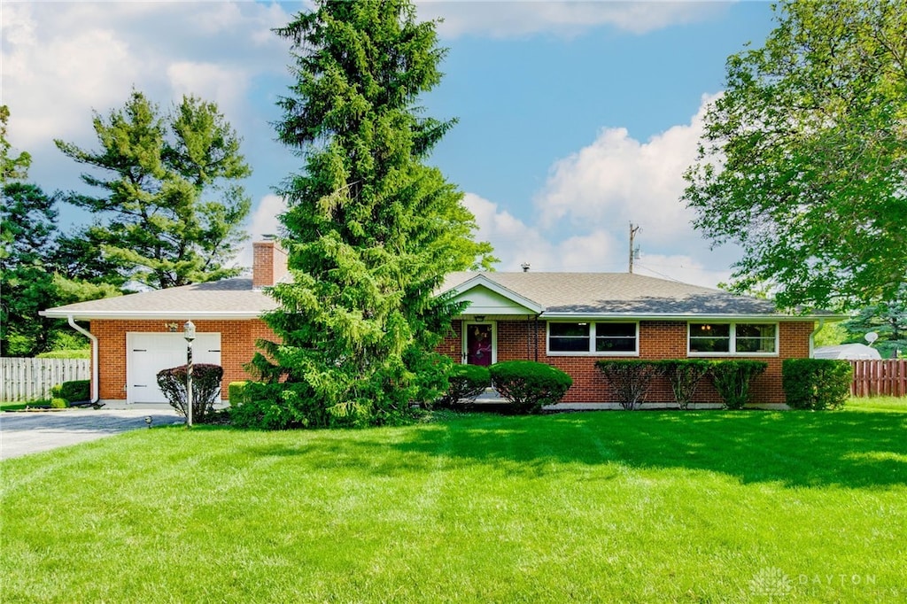 658 Omar Cir, Yellow Springs Vlg, OH 45387 - single story home featuring an attached garage, driveway, brick siding, and a chimney