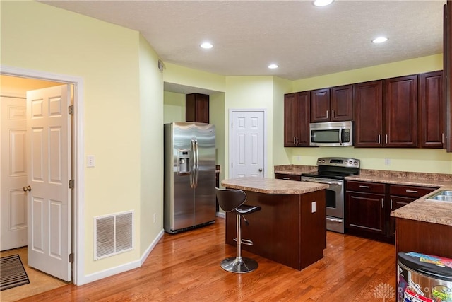 2385 Gerard Ct, Fairborn, OH 45324 - kitchen with appliances with stainless steel finishes, a center island, light wood finished floors, a kitchen breakfast bar, and recessed lighting