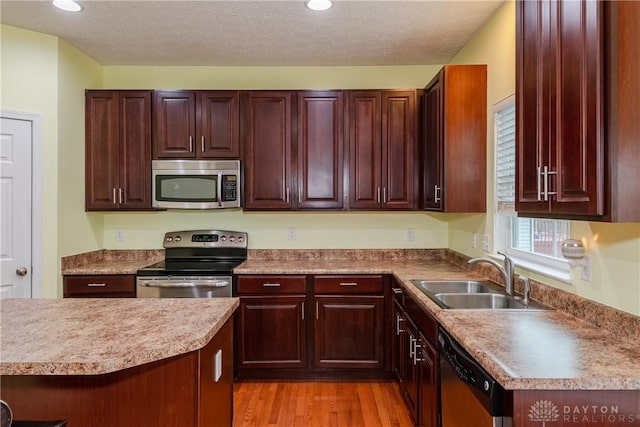 2385 Gerard Ct, Fairborn, OH 45324 - kitchen featuring stainless steel appliances, a sink, light wood finished floors, reddish brown cabinets, and recessed lighting