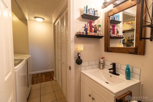 5864 Beecham Dr, Huber Heights, OH 45324 - bathroom featuring washer and clothes dryer, vanity, tile patterned flooring, a textured ceiling, and tasteful backsplash