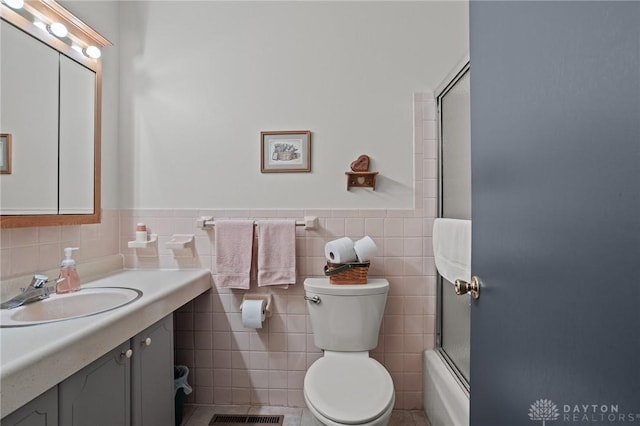6719 Morrow Dr, Clayton, OH 45415 - full bath featuring tile walls, vanity, toilet, a wainscoted wall, and shower / bath combination with glass door
