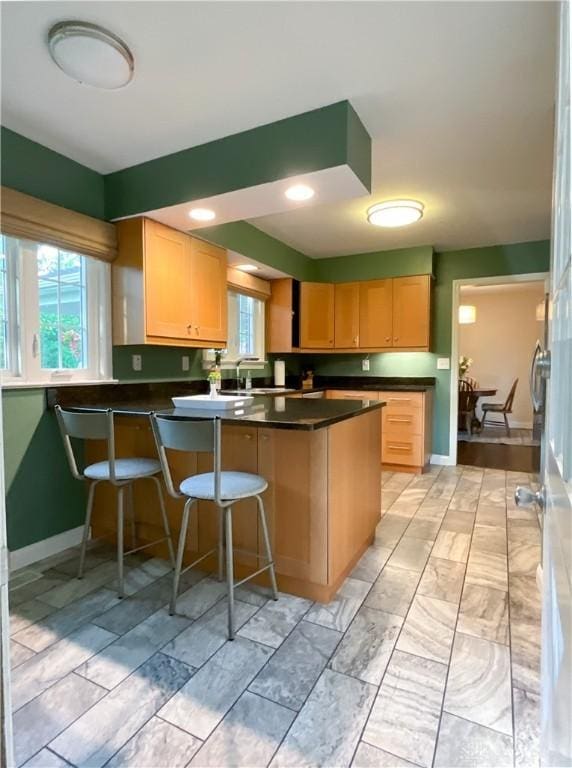 869 Maxwelton, Washington Twp, OH 45459 - kitchen with dark countertops, baseboards, a breakfast bar, a peninsula, and light brown cabinetry