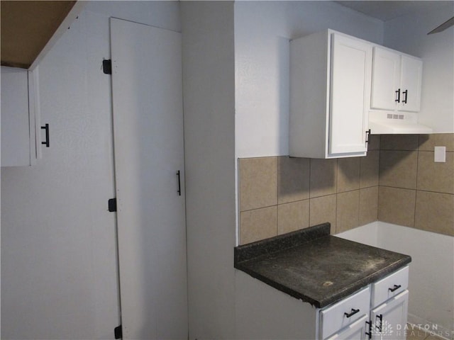 2455 Catalpa Dr, Dayton, OH 45406 - kitchen with under cabinet range hood, backsplash, white cabinets, and dark countertops