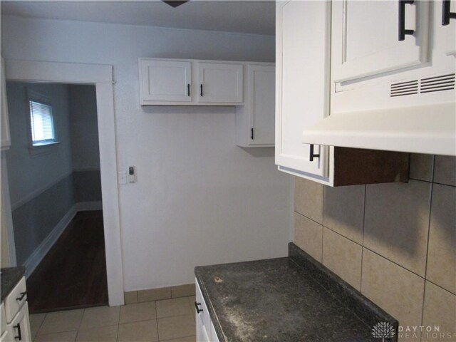 2455 Catalpa Dr, Dayton, OH 45406 - kitchen with white cabinets, dark stone countertops, under cabinet range hood, light tile patterned floors, and baseboards