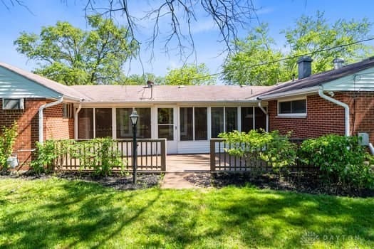 1108 Donson Dr, Kettering, OH 45429 - back of property with a sunroom, brick siding, a yard, and a deck