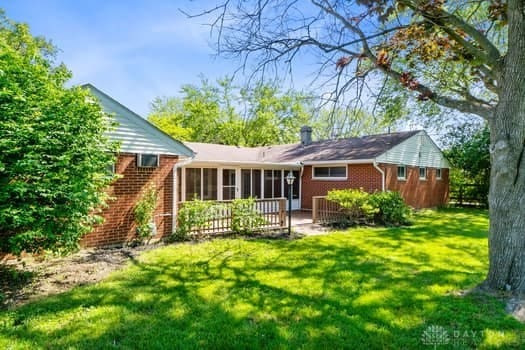 1108 Donson Dr, Kettering, OH 45429 - rear view of house featuring a sunroom, a yard, brick siding, and a chimney