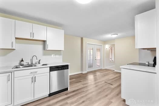 1108 Donson Dr, Kettering, OH 45429 - kitchen featuring stainless steel dishwasher, a sink, light countertops, white cabinets, and baseboards