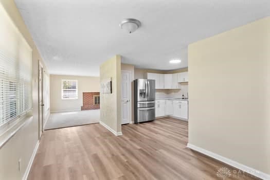 1108 Donson Dr, Kettering, OH 45429 - kitchen featuring stainless steel fridge with ice dispenser, white cabinetry, baseboards, and light wood-style floors
