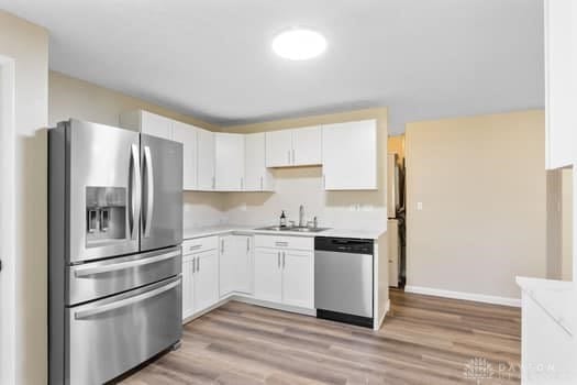 1108 Donson Dr, Kettering, OH 45429 - kitchen with appliances with stainless steel finishes, a sink, light countertops, and light wood-style floors