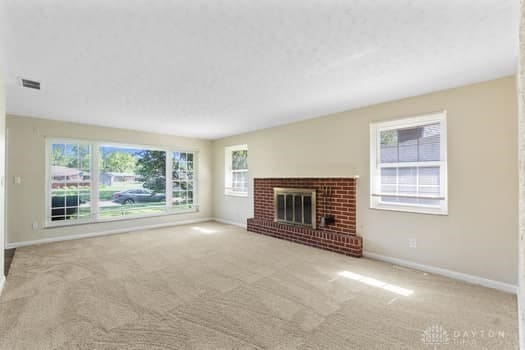 1108 Donson Dr, Kettering, OH 45429 - unfurnished living room with baseboards, carpet flooring, and a brick fireplace