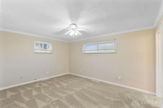 1108 Donson Dr, Kettering, OH 45429 - spare room featuring crown molding, a ceiling fan, light carpet, and baseboards
